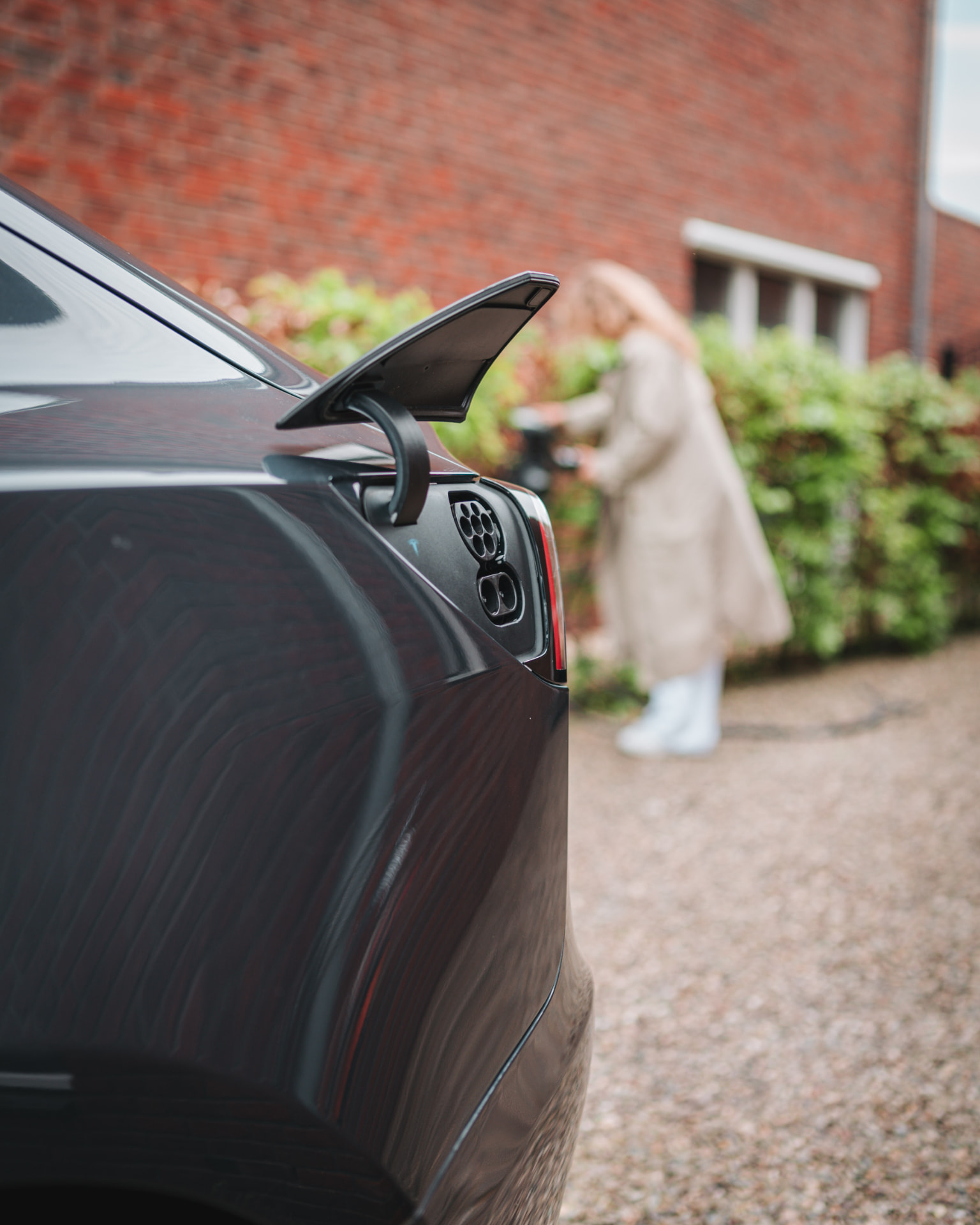 Vrouw sluit een laadkabel aan op een elektrische auto